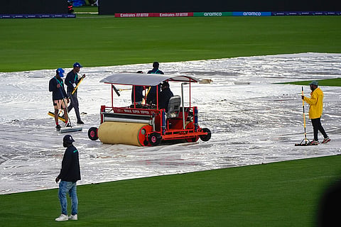 Groundsmen clear water from the covers 